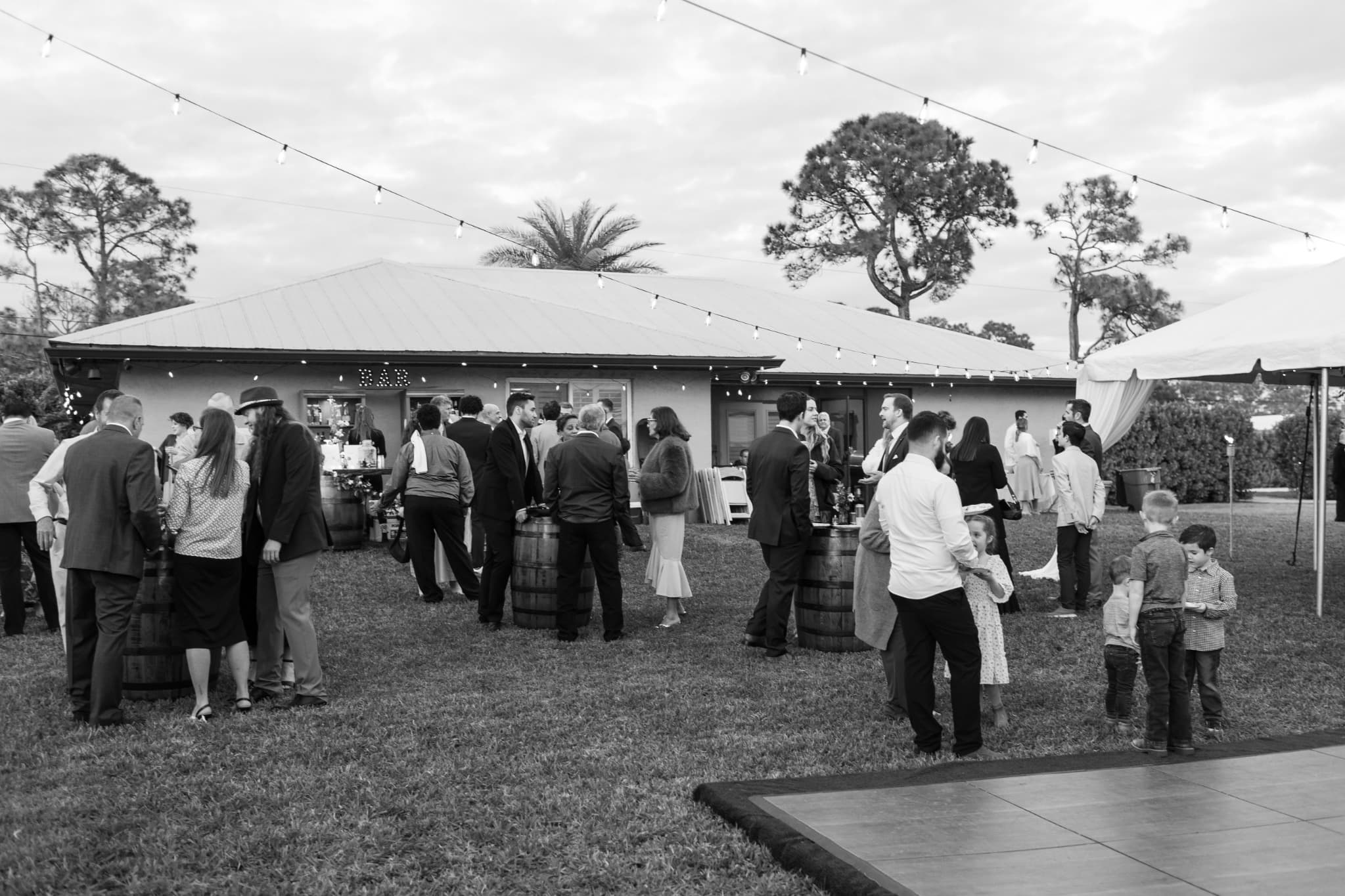 Black and white outdoor wedding reception with whiskey barrels